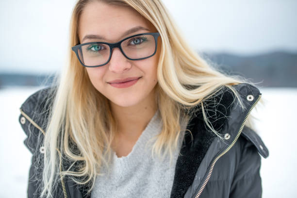 portrait of a beautiful smiling teenage girl looking at camera outdoors on snow - snow glasses imagens e fotografias de stock