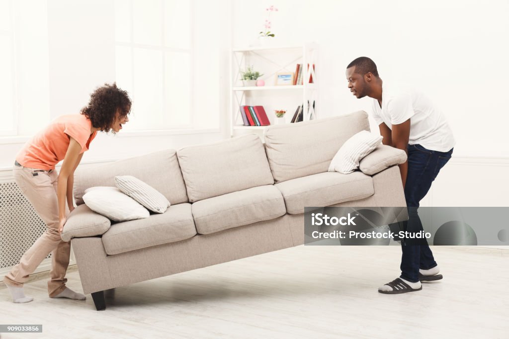 Pareja afroamericana colocando el sofá en casa nueva - Foto de stock de Nuevo libre de derechos