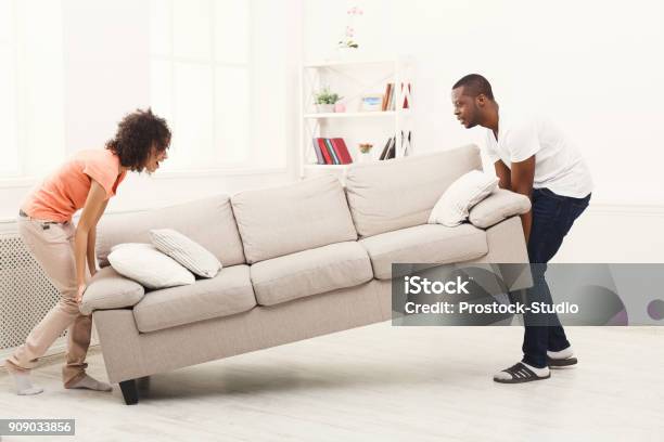 Pareja Afroamericana Colocando El Sofá En Casa Nueva Foto de stock y más banco de imágenes de Nuevo