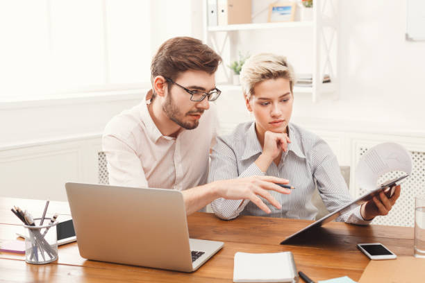 istock Couple of young colleagues working at modern office 909036744