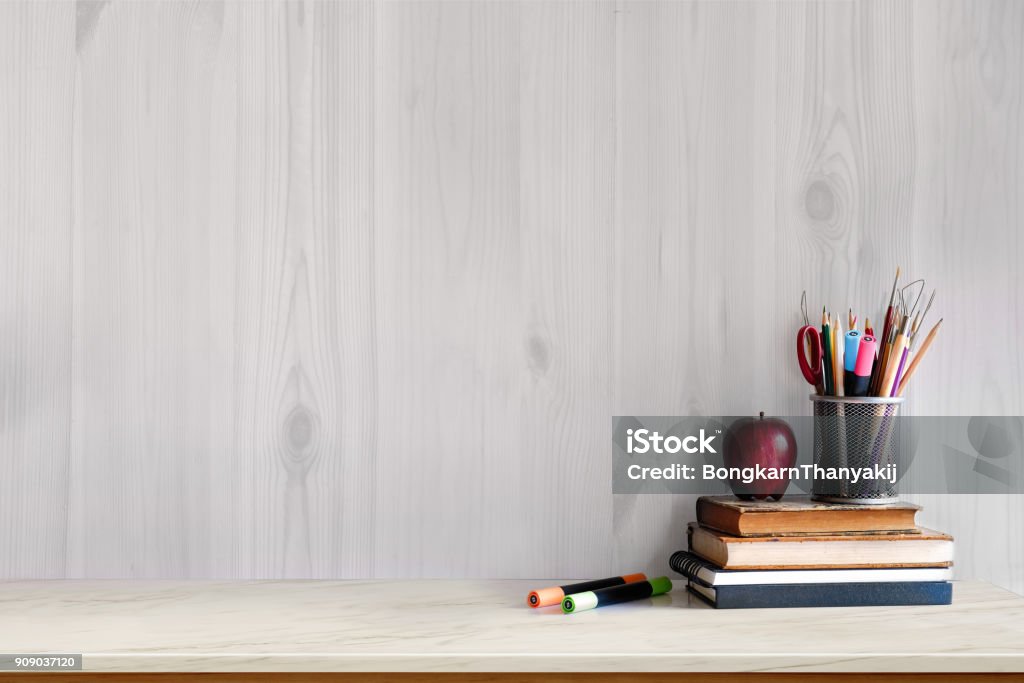 White marble table with vintage books, red fruit and supplies. Workspace with copy space for products display montage. mock up concept. Classroom Stock Photo