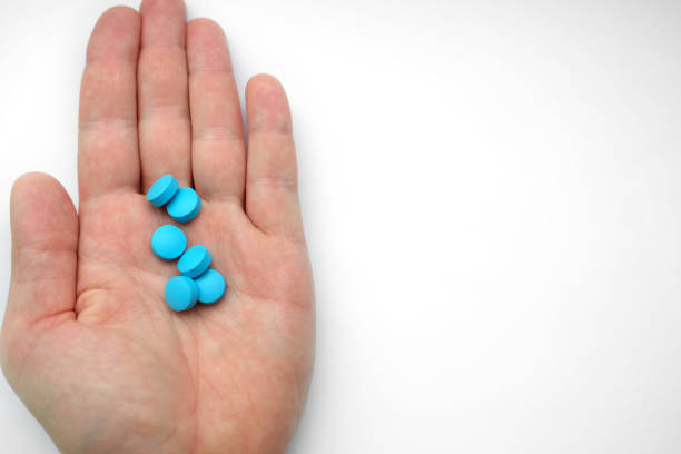 istock hand of man holding blue pills 909037522