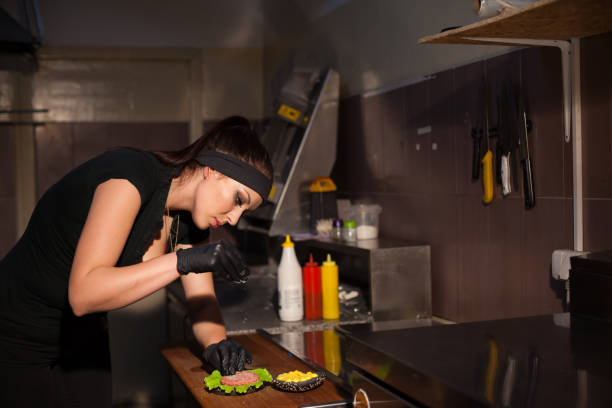 istock woman chef in the kitchen preparing a hamburger sandwich 909037716