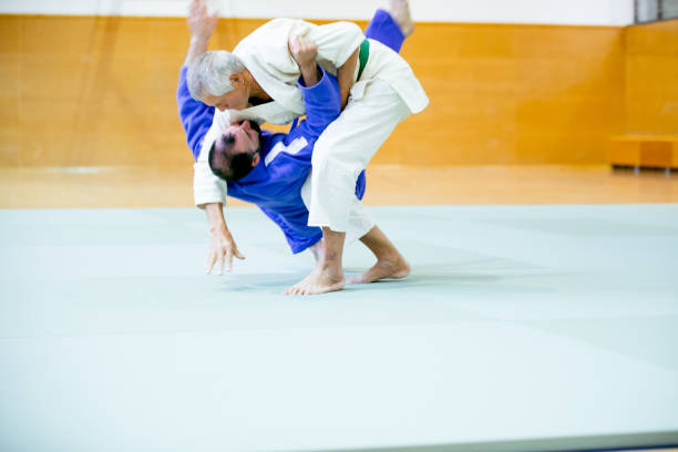 The two judokas fighters fighting men on gray studio background