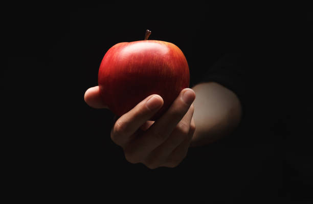 istock Red ripe apple on male hand, isolated on black 909041944