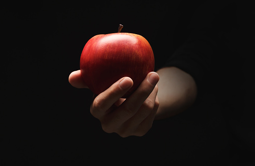 Red ripe apple on male hand, isolated on black