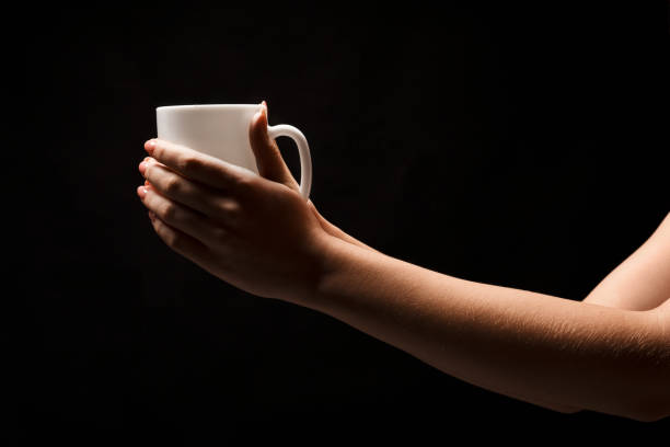 istock Woman holding white coffee cup on black background 909044644