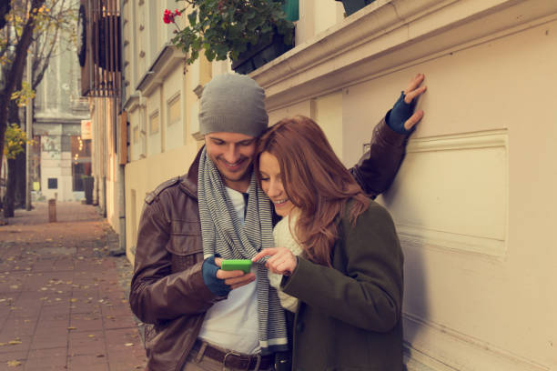 istock Attractive young couple in love using cellphone on the street. 909044828