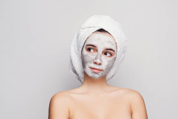 istock Beautiful girl with applied clay mask at white background 909045310