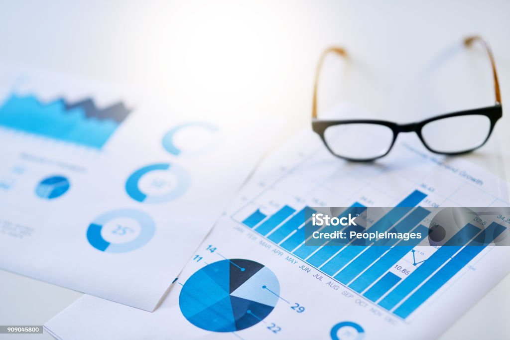 It all adds up in the end Shot of business documentation and glasses on an office desk Finance Stock Photo