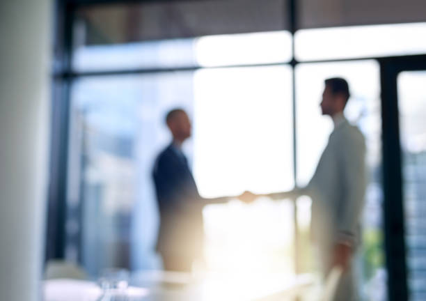 Building business relationships Blurred shot of two businessmen shaking hands in a modern office business relationship photos stock pictures, royalty-free photos & images
