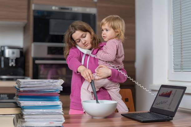 Multitasking mother is babysitting and working at home.