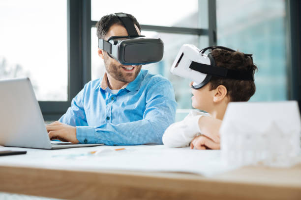 istock Cheerful father and son in VR headsets discussing experience 909048680
