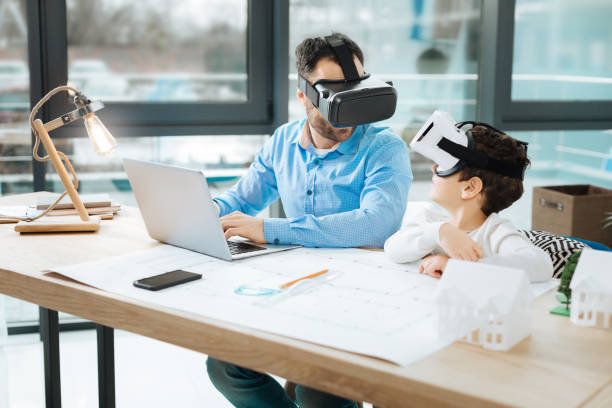 istock Little boy in VR headset chatting with father at work 909048750