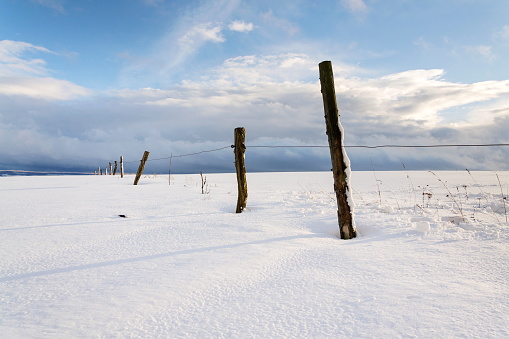 Vintage wooden fence poles in snowy winter country sunny day, weather forecast concept