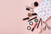 Beauty products and a gift bag flat lay on pink background
