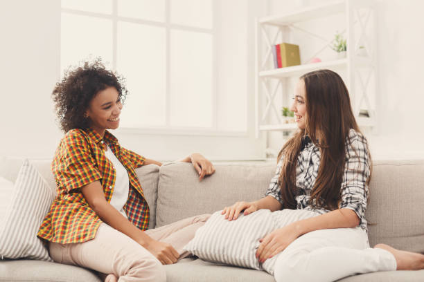 istock Two young female friends conversing at home 909066204