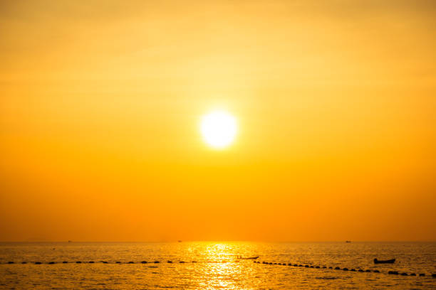 Sunset over sea below a yellow sun in a yellow sky at fall