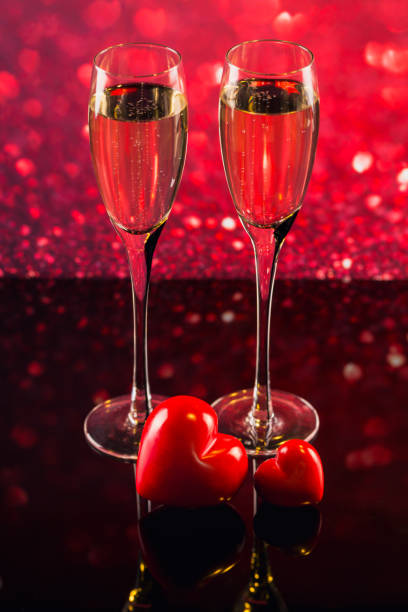 istock Two glasses of champagne with red heart shape bokeh on background. 909068942