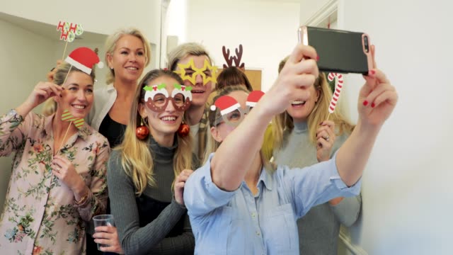 A group of office workers celebrating Christmas together taking a selfie.