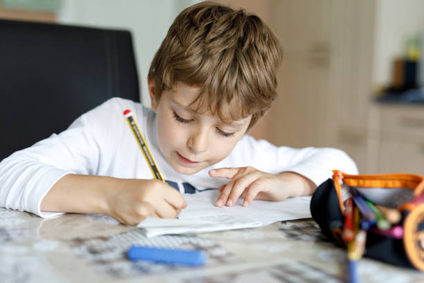Tired kid boy at home making homework writing letters with colorful pens Tired little kid boy at home making homework at the morning before the school starts. Little child doing excercise, indoors. Elementary school and education math homework stock pictures, royalty-free photos & images