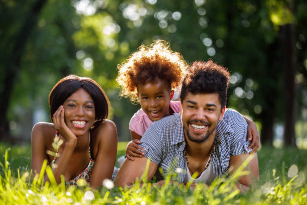 istock Happy family lying down on grass in park 909070650