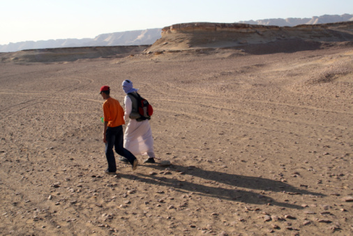 Two native arabic people walking in the desert