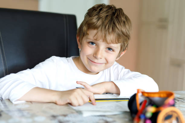 Tired little kid boy at home making homework at the morning before the school starts. Little child doing excercise, indoors. Elementary school and education