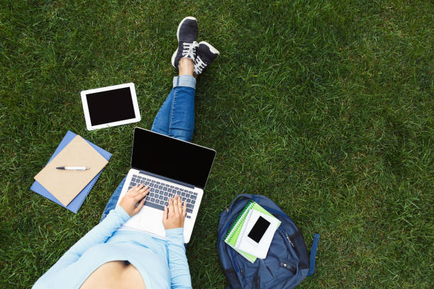 istock Girl with laptop on the grass 909080386
