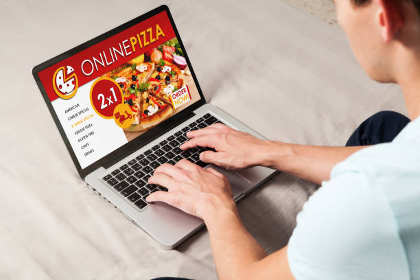 istock Man ordering pizza by internet with a laptop computer, sitting at home. 909080984