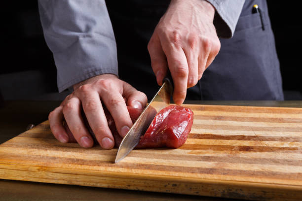 istock Chef cutting filet mignon on wooden board at restaurant kitchen 909092668