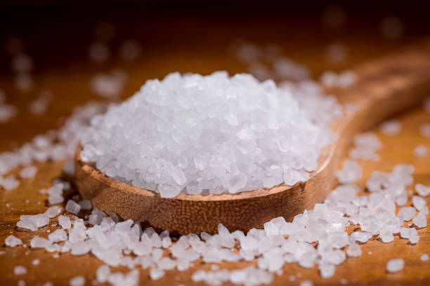 istock Sea salt crystals closeup in wooden spoon on a kitchen table. 909097744