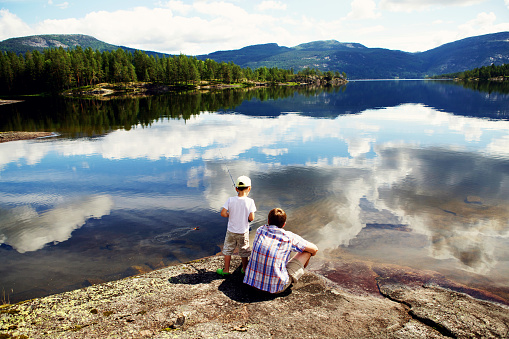 Father teaches his son to catch fish in beautiful countryside of Norway, July 2013.