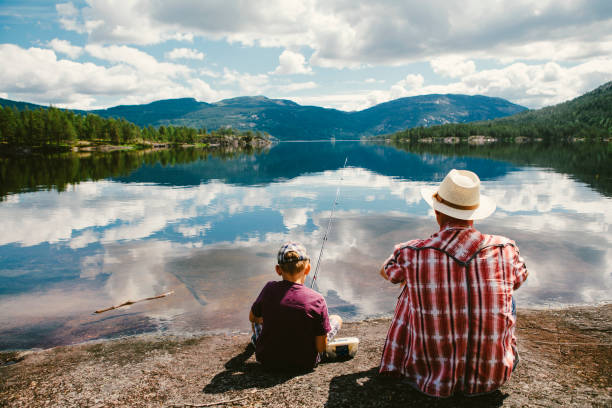 Grandson and grandpa are fishing in Norway. Grandfather is teaching his young grandson how to catch fish. Norway, July 2013. fjord photos stock pictures, royalty-free photos & images