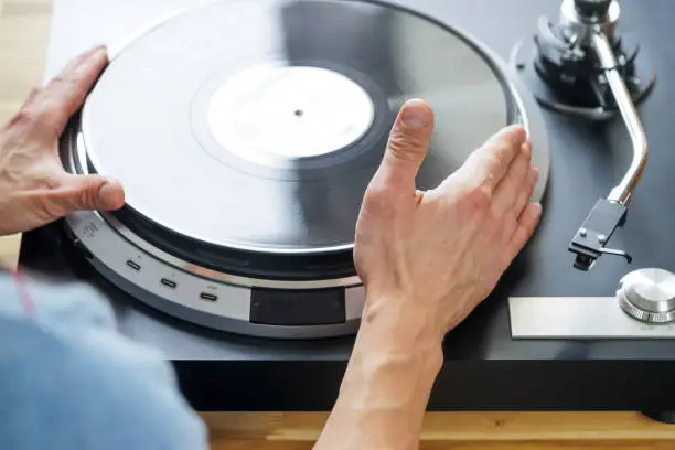 Photo of Hands placing record on turntable close-up