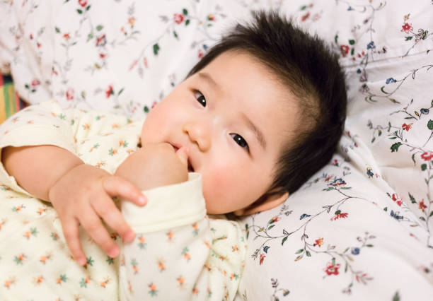 istock Cute baby smiling close-up thumb sucking 909105496