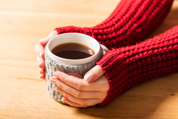 istock Hot mug of tea warming woman's hands in retro jumper. 909106256