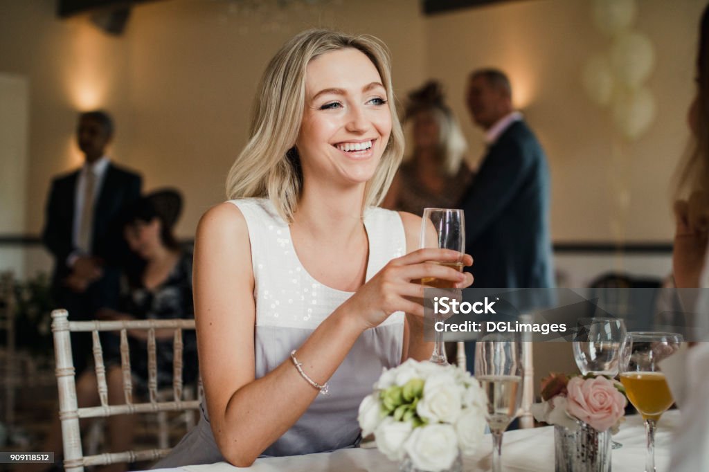 Beautiful Guest at a Wedding Young woman is sitting at a table at a wedding with a glass of champagne. Wedding Guest Stock Photo