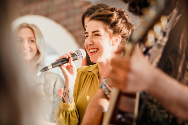 Fun Wedding Entertainers Entertianment at a wedding. A female singer is interacting with the crowd while a man plays an acoustic guitar. singing stock pictures, royalty-free photos & images