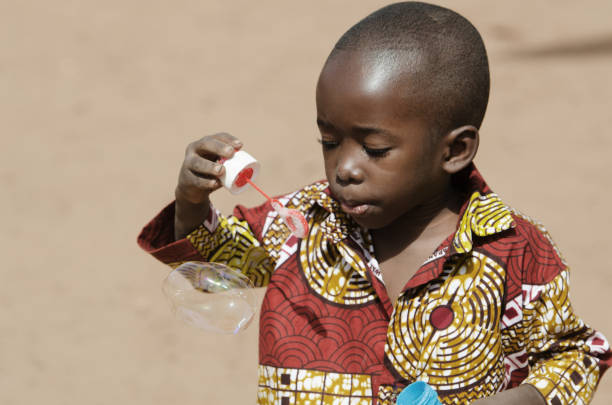 istock Handsome African baby boy having fun outdoors with soap bubbles 909126530