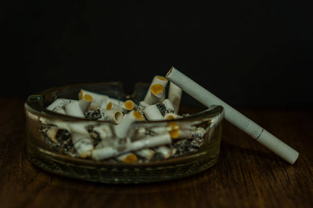 istock Cigarette butts in a glass ashtray. One cigarette is not lit. 909127020