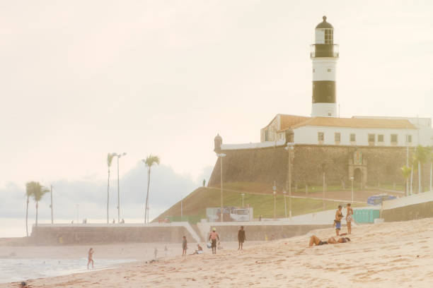 Tourists enjoy Barra beach during sunset with the lighthouse in the background Salvador de Bahia, Brazil - May 14, 2017: Tourists enjoy Barra beach during sunset with the lighthouse in the background barra beach stock pictures, royalty-free photos & images