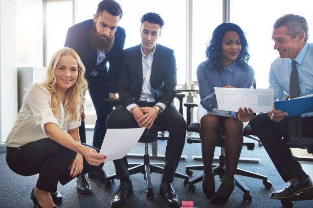 istock Smiling colleagues discussing paperwork together in an office 909133382