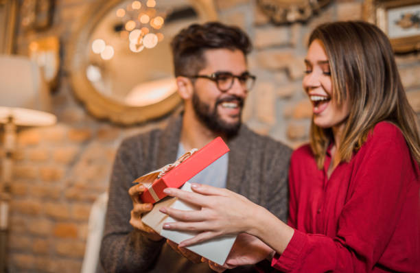 Cheerful young woman receiving a gift from her boyfriend. Cheerful young woman receiving a gift from her boyfriend. valentines day holiday stock pictures, royalty-free photos & images