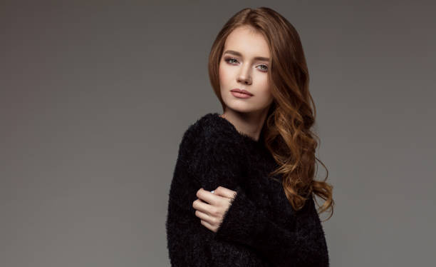 Kobieta ubrana jest w wygodny czarny sweterek, będący ucieleśnieniem omawianej w artykule esencji wygody i stylu.