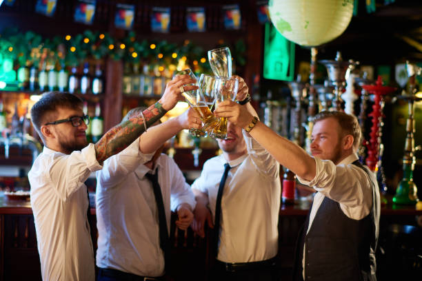 Excited managers celebrating success at pub Group of hilarious young friends having fun after work drinking brewed beer in pub stag stock pictures, royalty-free photos & images