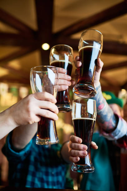 celebratory toast with pints of stout beer - irish culture beer drinking pub imagens e fotografias de stock