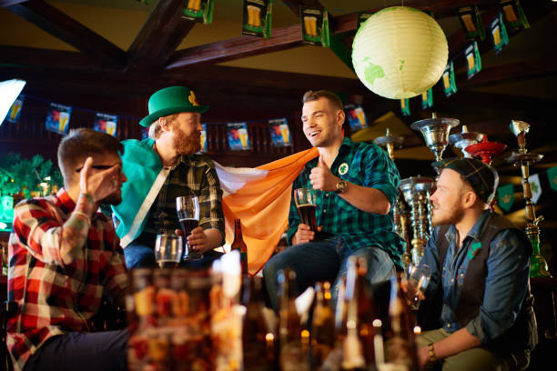 happy friends chatting with beer in irish pub - irish culture beer drinking pub imagens e fotografias de stock