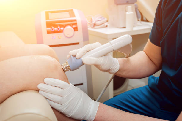 shock wave therapy. the magnetic field, rehabilitation. physiotherapist doctor performs surgery on a patient's knee - electrode imagens e fotografias de stock