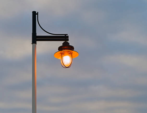 istock Lighted street lamp against a partly cloudy sky with copy space. 909157316